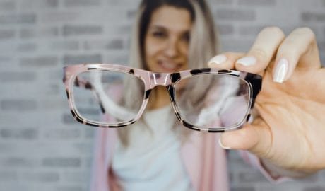 Picture close up of a blonde hair lady holding glasses in her hand.