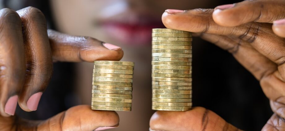 Closing the wage gape. A woman holding out her hands for a closeup. In her hands are two stacks of coins. One stack has more coins than the other.