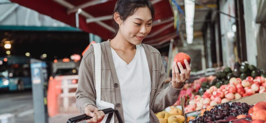 Therapy and Health Coaching - A woman wearing a cardigan holding a red apple.