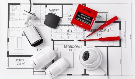 A collection of home safety and monitoring equipment all sitting on top of a blueprint for a small home.