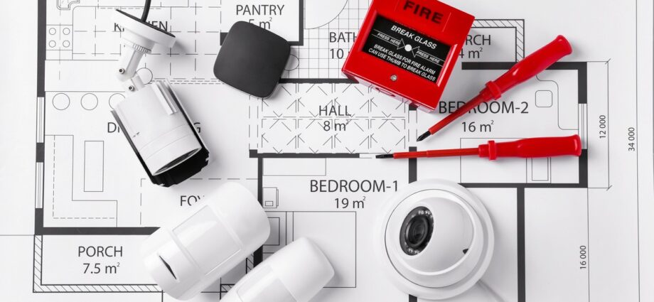 A collection of home safety and monitoring equipment all sitting on top of a blueprint for a small home.