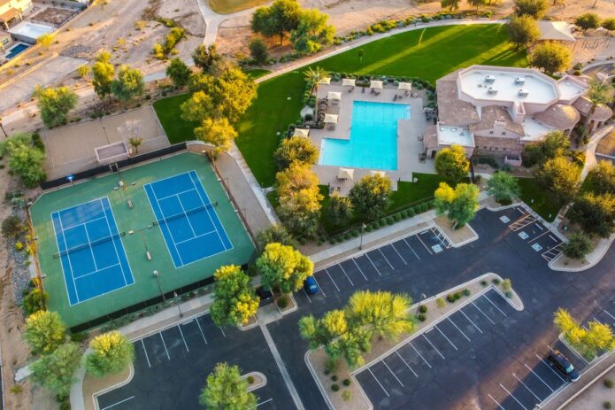 Improving Your Community Center: 4 Practical Ways to Get It Done Easily 3 An aerial scene of a community center with tennis courts, a swimming pool, trees, lawns, and parking areas.